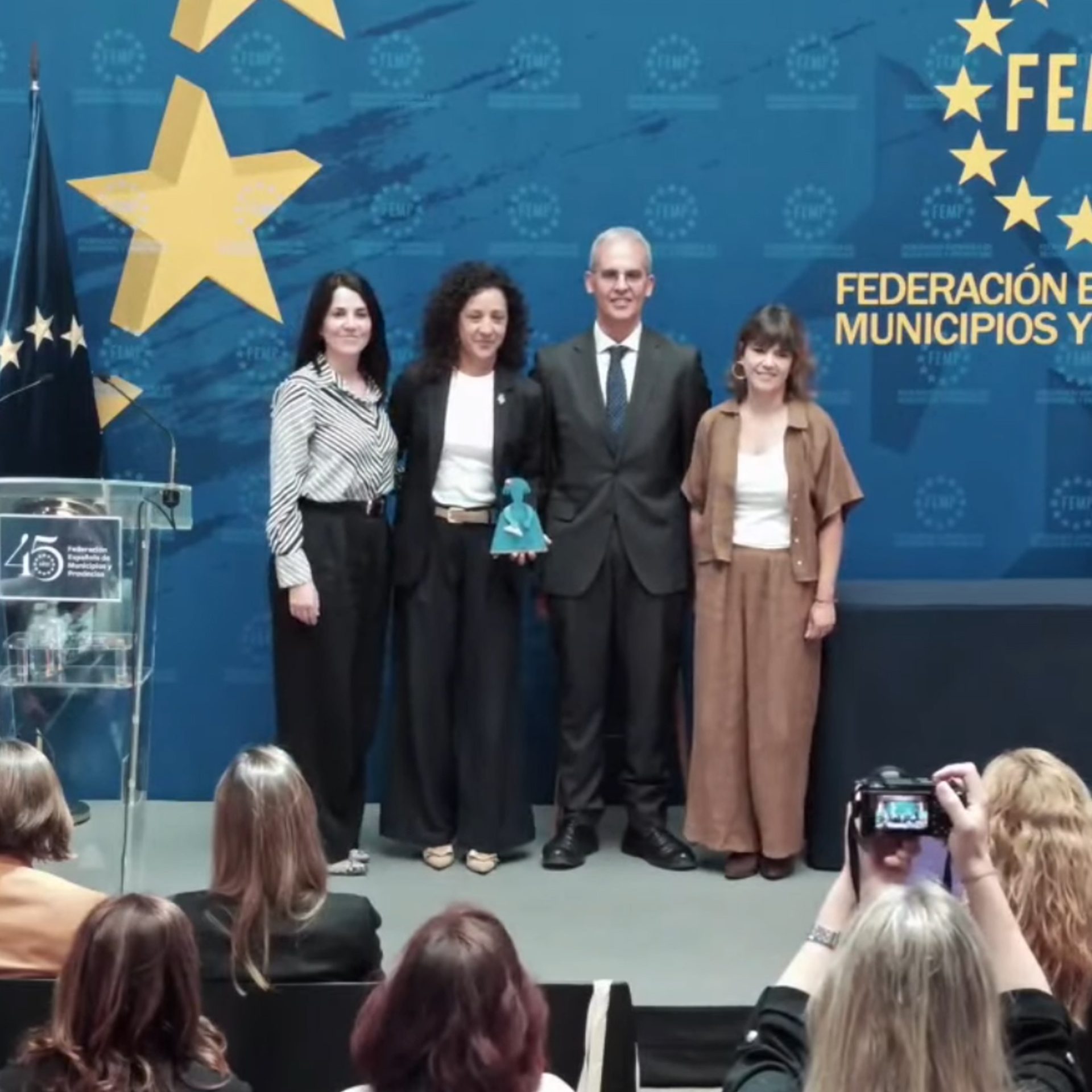El nombre de Pinoso ha sonado hoy con fuerza en Madrid 📍. El Patio de la Federación Española de Municipios y Provincias (FEMP) 🏛️ ha sido el escenario donde nuestro municipio ha recibido un importante reconocimiento de categoría nacional 🏆: uno de los premios del X Concurso de buenas prácticas locales contra la violencia sobre las mujeres 🚺⚖️.

La alcaldesa, Silvia Verdú 👩‍💼, acompañada por la edil de Igualdad, María José Moya 🤝, y por la coordinadora Laura Martínez 📋, se ha desplazado a la capital para recoger este galardón 🎖️ concedido por la Delegación del Gobierno y la FEMP, que sitúa a Pinoso a la vanguardia de la “Mejora de la respuesta institucional” contra la violencia machista 💜.

El municipio ha sido premiado por su capacidad para optimizar la coordinación y el trabajo en red 🔗 entre las diferentes autoridades y organismos responsables, reconociendo directamente el trabajo en red que se realiza gracias a la Mesa Local de Coordinación Institucional contra la VG 🧩 y al Protocolo de Actuación Conjunta 📑, una herramienta clave para proteger de forma rápida y eficaz 🛡️ a las mujeres y la infancia de Pinoso 👩‍👧‍👦.

“Eliminar la violencia de género es una cosa de todos y todas y desde las administraciones, muy especialmente, estamos obligados a fomentar esa coordinación y colaboración interinstitucional fundamental para conseguirla”, ha concluido la alcaldesa en Madrid, reafirmando el compromiso inquebrantable de Pinoso en esta lucha.